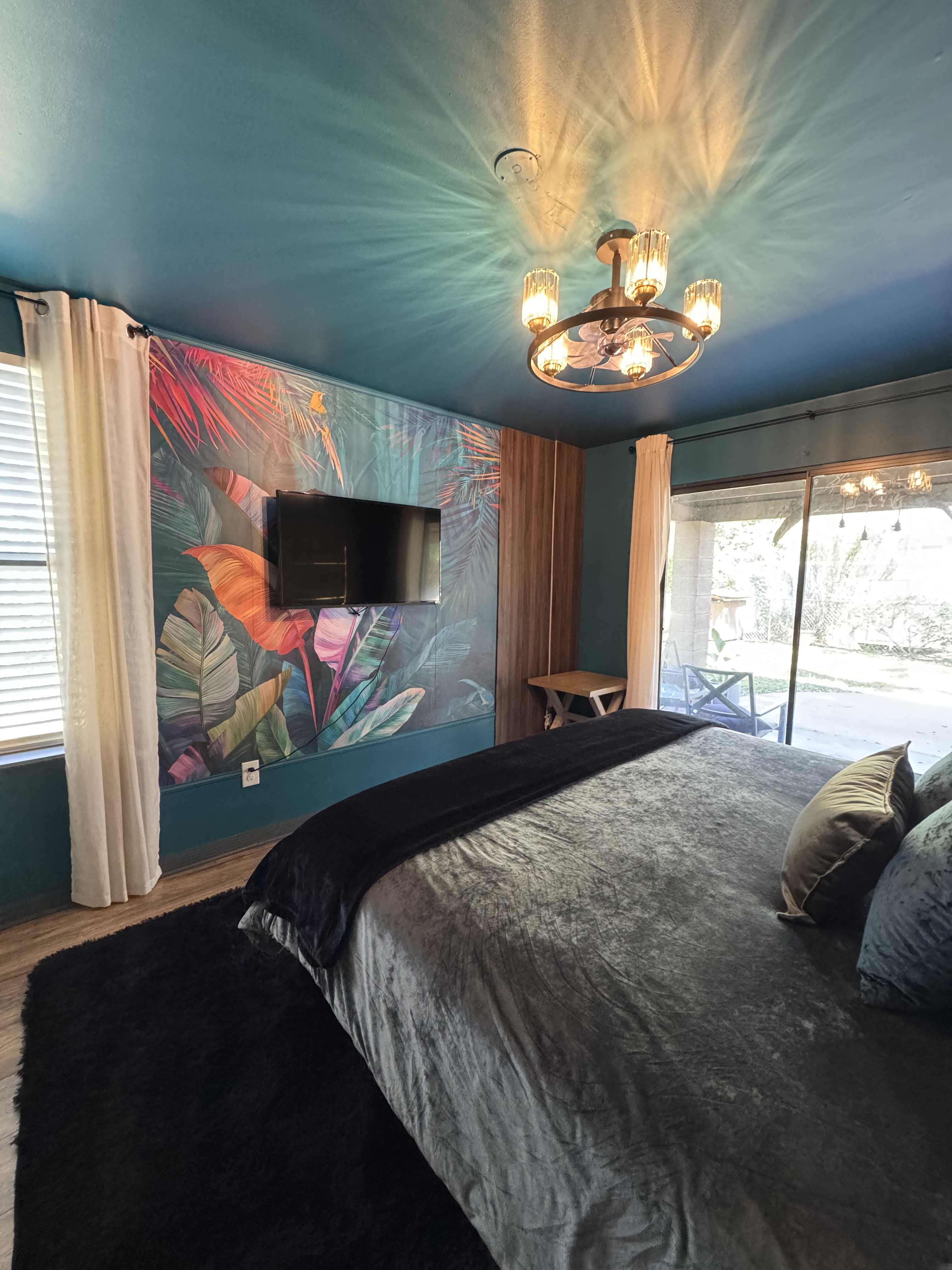 Feher's Lair — master bedroom with tropical mural wall, velvet bedding, garden view