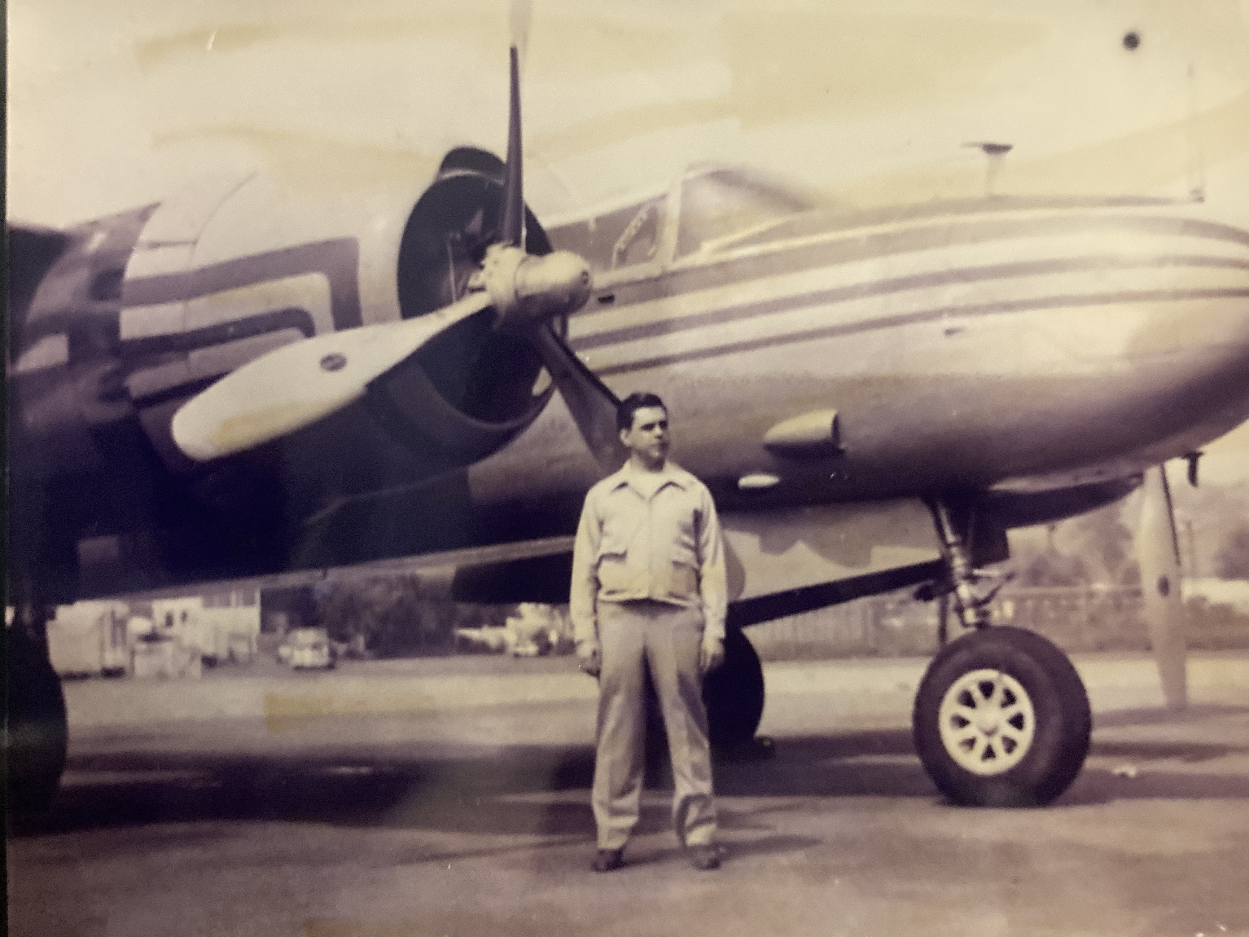 Young Arthur J. Feher standing before a propeller fighter aircraft